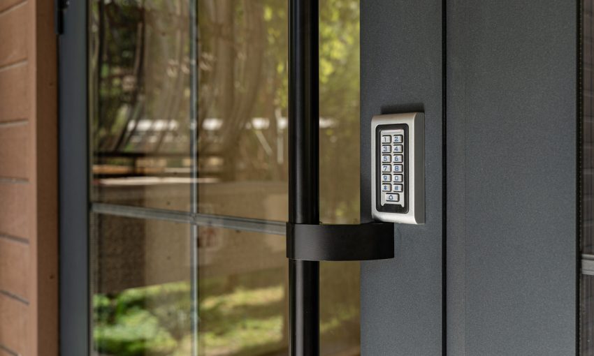 Closeup of modern door with electronic keypad access control system, secure building entrance technology.