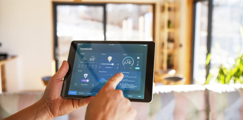 Unrecognisable man using tablet with smart home control functions at home.
